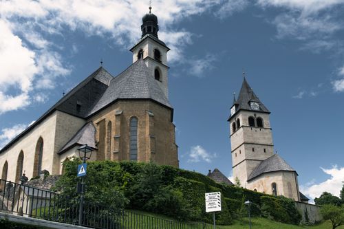 Free Historic church towers in Kitzbühel, Austria stand tall against a bright blue sky. A landmark view. Stock Photo
