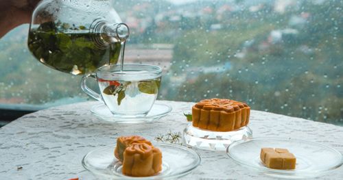 Free A warm scene of tea pouring and mooncakes on a rainy fall day, perfect for autumn reflections. Stock Photo