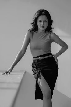 Monochrome portrait of a confident woman in stylish attire posing indoors.