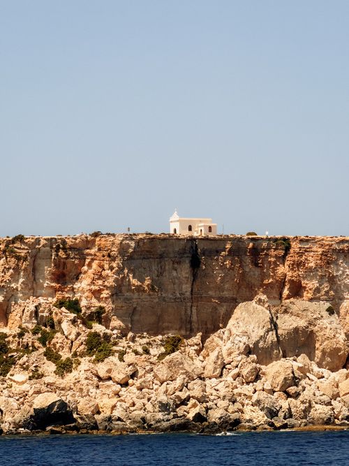 Free Picturesque limestone cliffs and chapel in Malta under clear blue sky. Ideal for travel and nature themes. Stock Photo