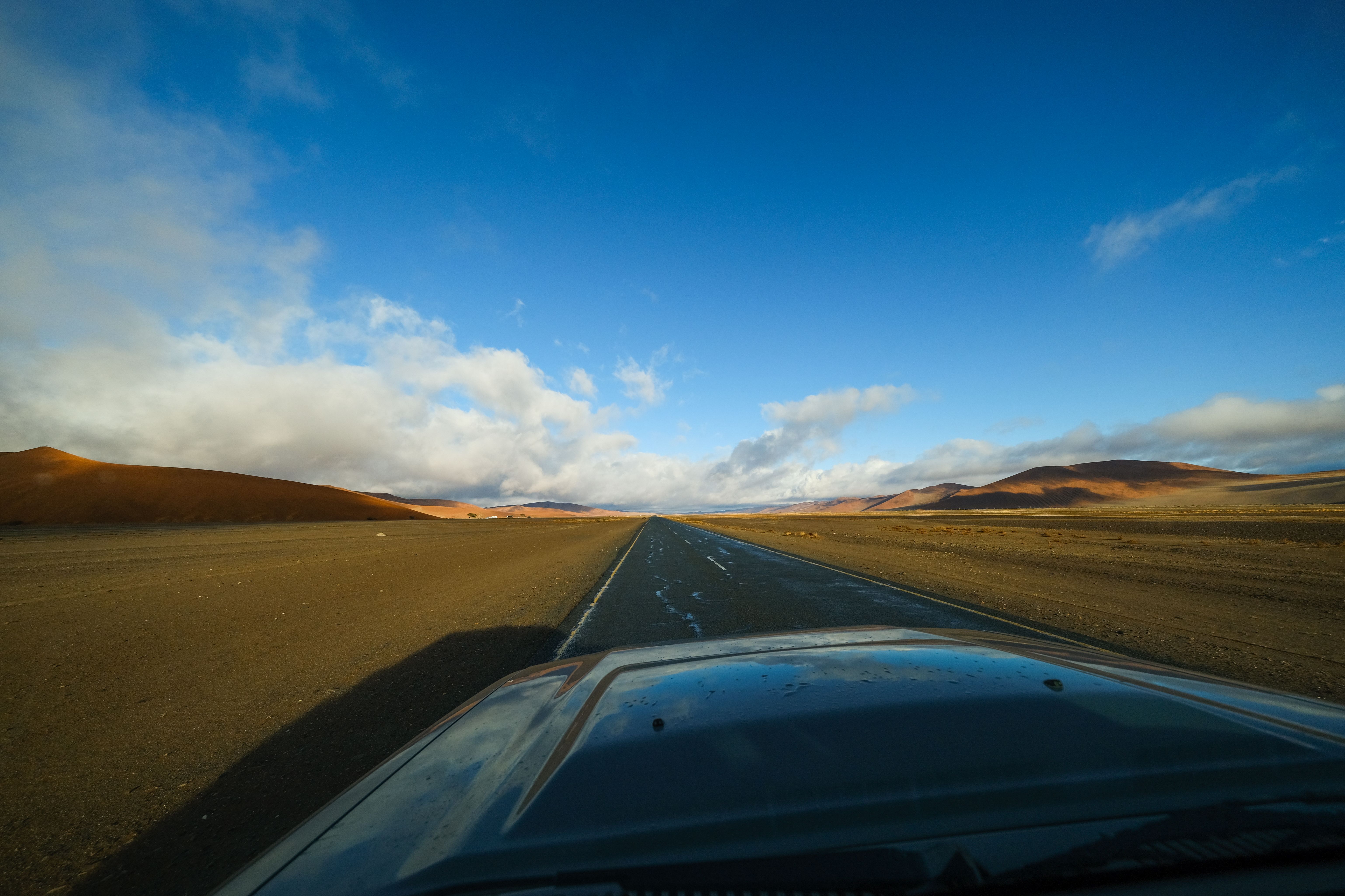 Expansive road through Namibia's Hardap region desert under a vast blue sky.