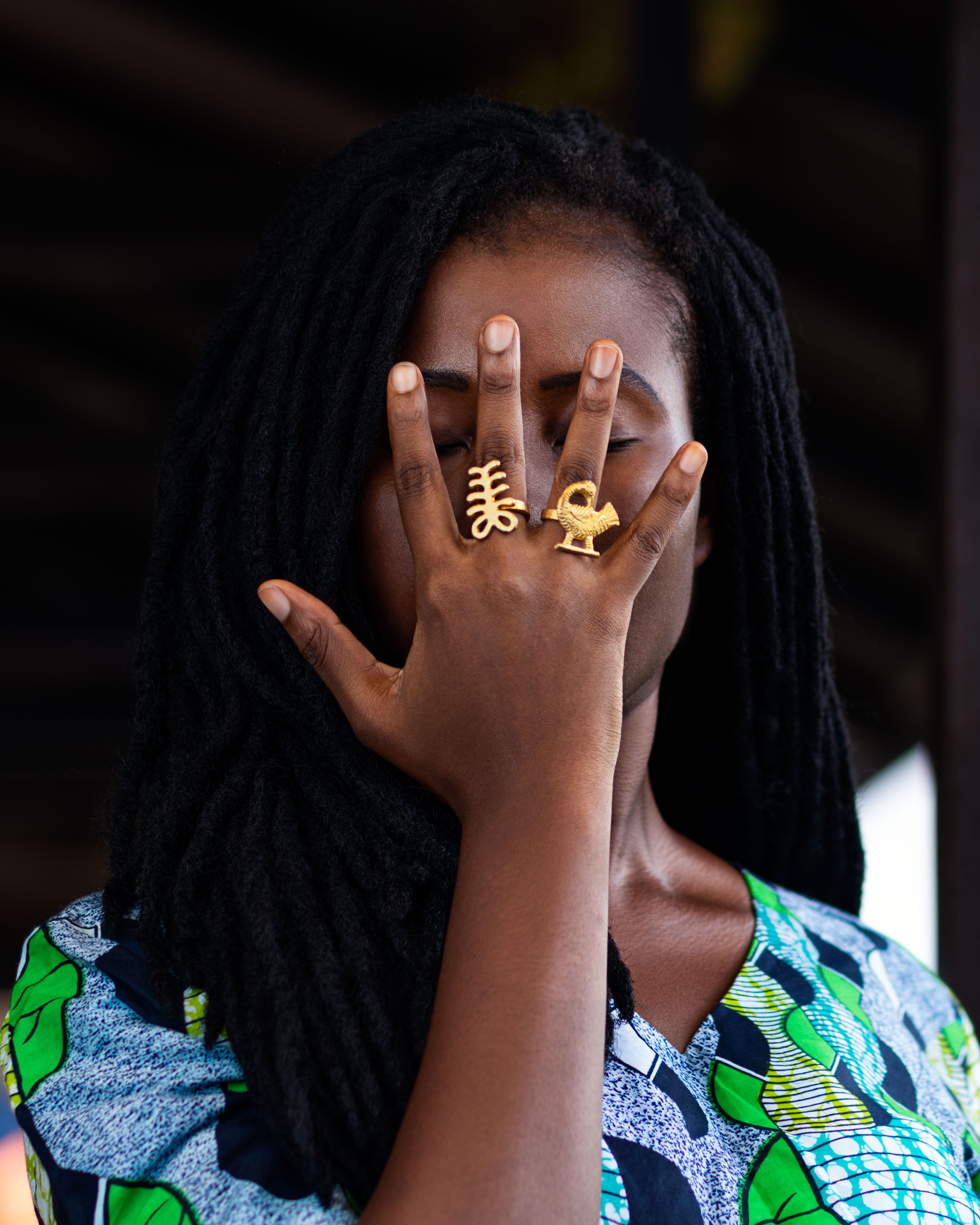 Portrait of a woman in Ghana showcasing cultural Adinkra symbol rings and vibrant attire.