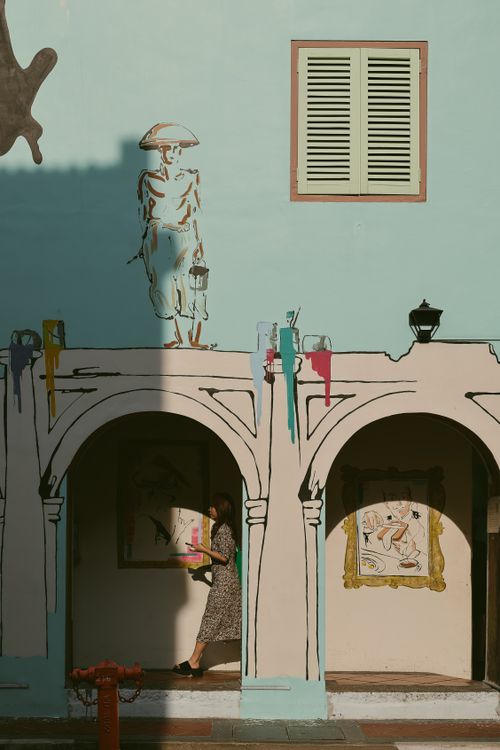 Free A person admires vibrant street art on a pastel building wall during daylight. Stock Photo