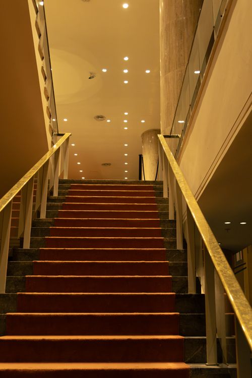 Free A red carpeted staircase with modern design and warm lighting in a contemporary building interior. Stock Photo