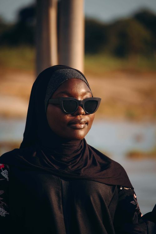 Free Stylish woman in a hijab and sunglasses enjoying a sunny day outdoors. Stock Photo