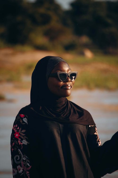 Free A woman enjoying a sunny day outdoors, wearing sunglasses and a hijab. Stock Photo