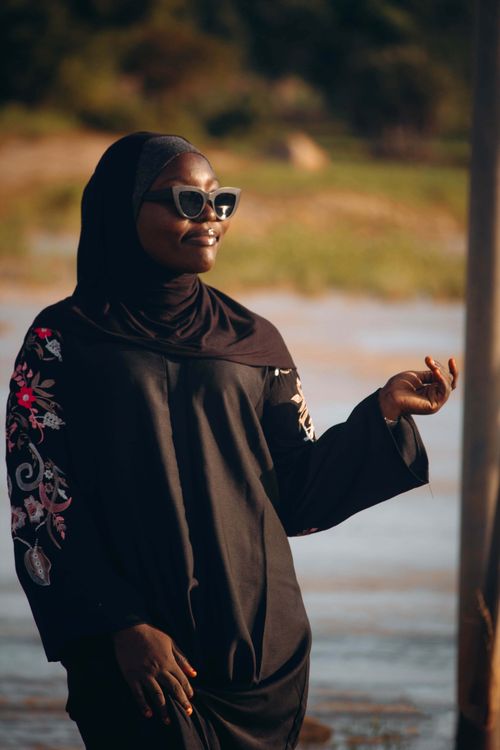 Free Elegant woman in hijab and sunglasses enjoying a warm sunny day by the water. Stock Photo