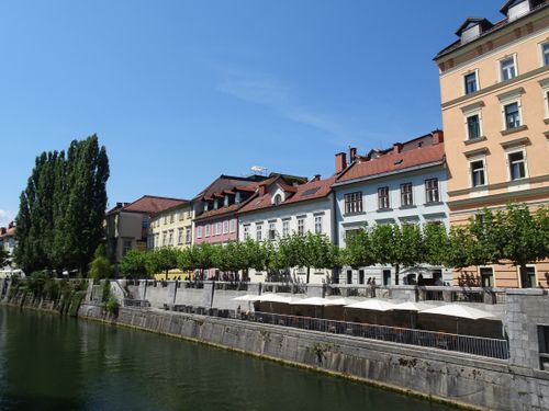 Free Explore the vibrant architecture along the river in Ljubljana, Slovenia, under clear summer skies. Stock Photo