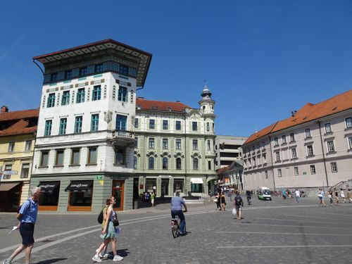 Free Discover the vibrant atmosphere of Ljubljana's historic square with stunning architecture and blue skies. Stock Photo