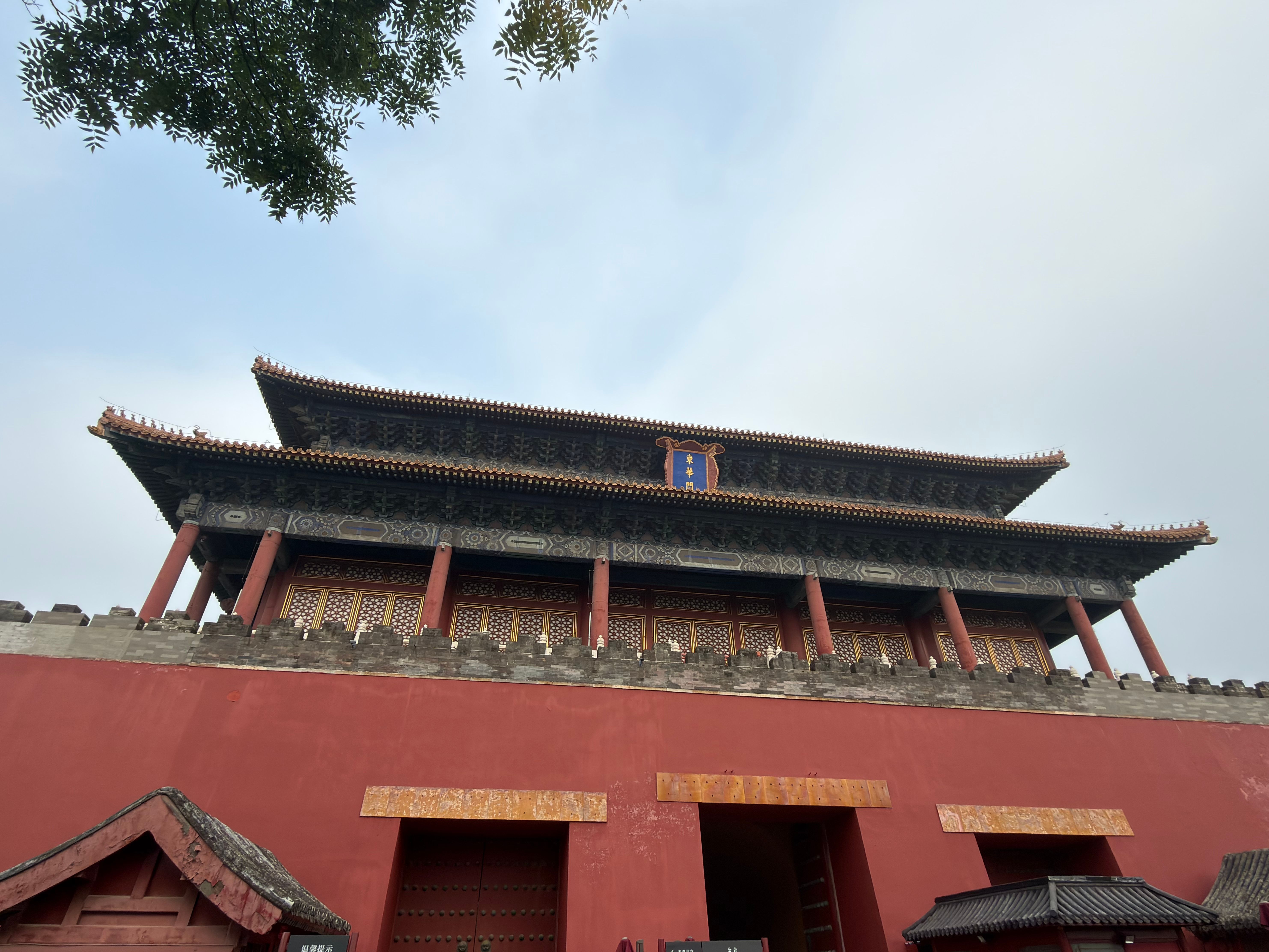View of traditional Chinese architecture with a red wall and intricate roof design in Beijing, China.