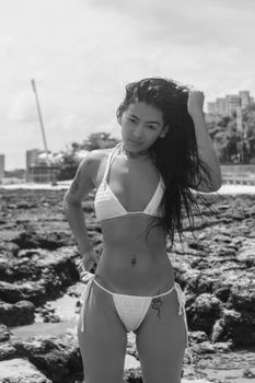 Black and white portrait of a woman in swimwear on rocky beach in Ceará, Brazil.