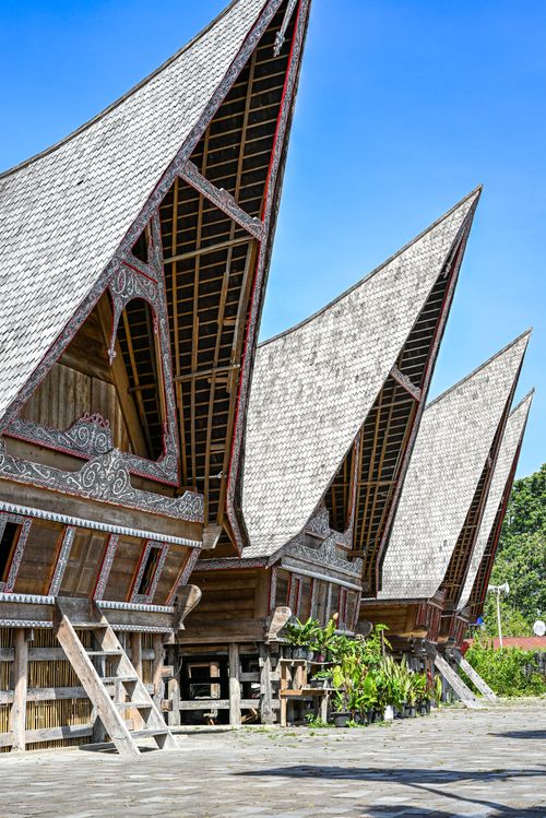 Free A row of iconic Batak Toba houses with unique roofs under a clear blue sky. Stock Photo