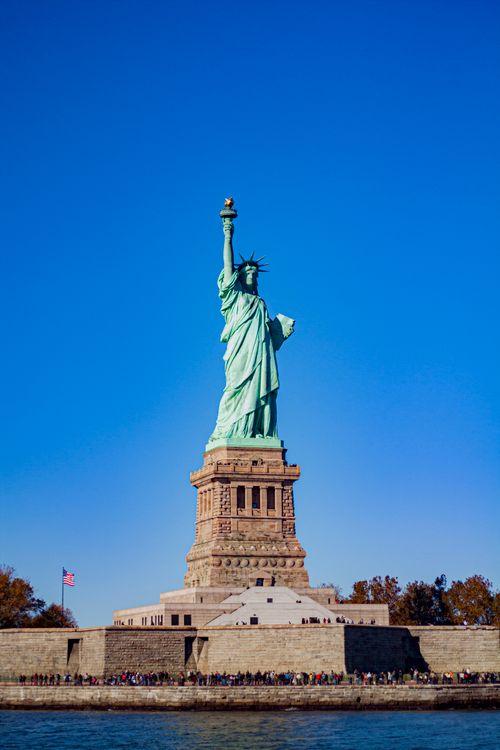 Free The iconic Statue of Liberty under a bright blue sky, symbolizing freedom and welcoming visitors to New York City. Stock Photo