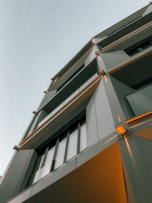 Free Low-angle view of a modern building exterior in Poznań, showcasing geometric lines and urban design. Stock Photo
