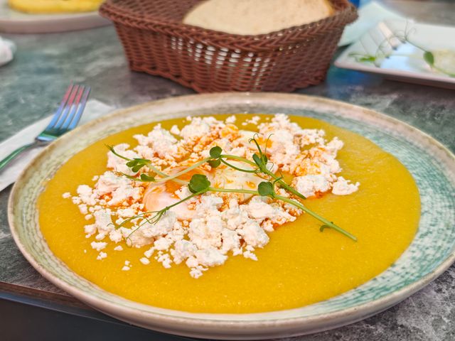 A delectable pumpkin soup garnished with cheese and microgreens on a rustic table setting.