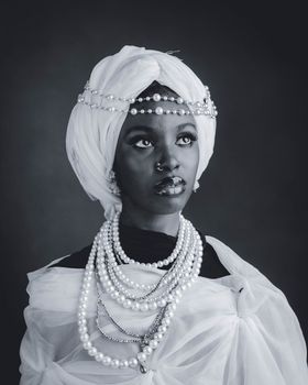 Striking black and white portrait of a woman in pearls and a turban, exuding elegance and grace.