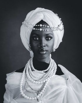 Striking black and white portrait of a woman wearing traditional African jewelry and headwrap.