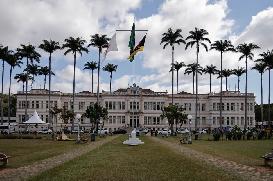 Elegant municipal building in Juiz de Fora, Brazil, surrounded by palm trees under a cloudy sky.