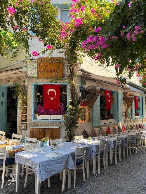 Free A picturesque street cafe in Alacati, Turkey, adorned with vibrant flowers and Turkish flags. Stock Photo