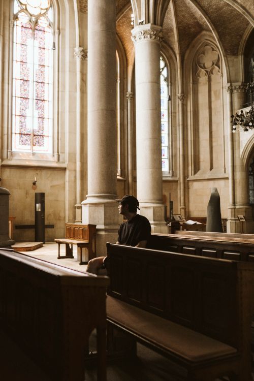 Free A person sitting in a serene historic cathedral, capturing a moment of reflection and peace. Stock Photo