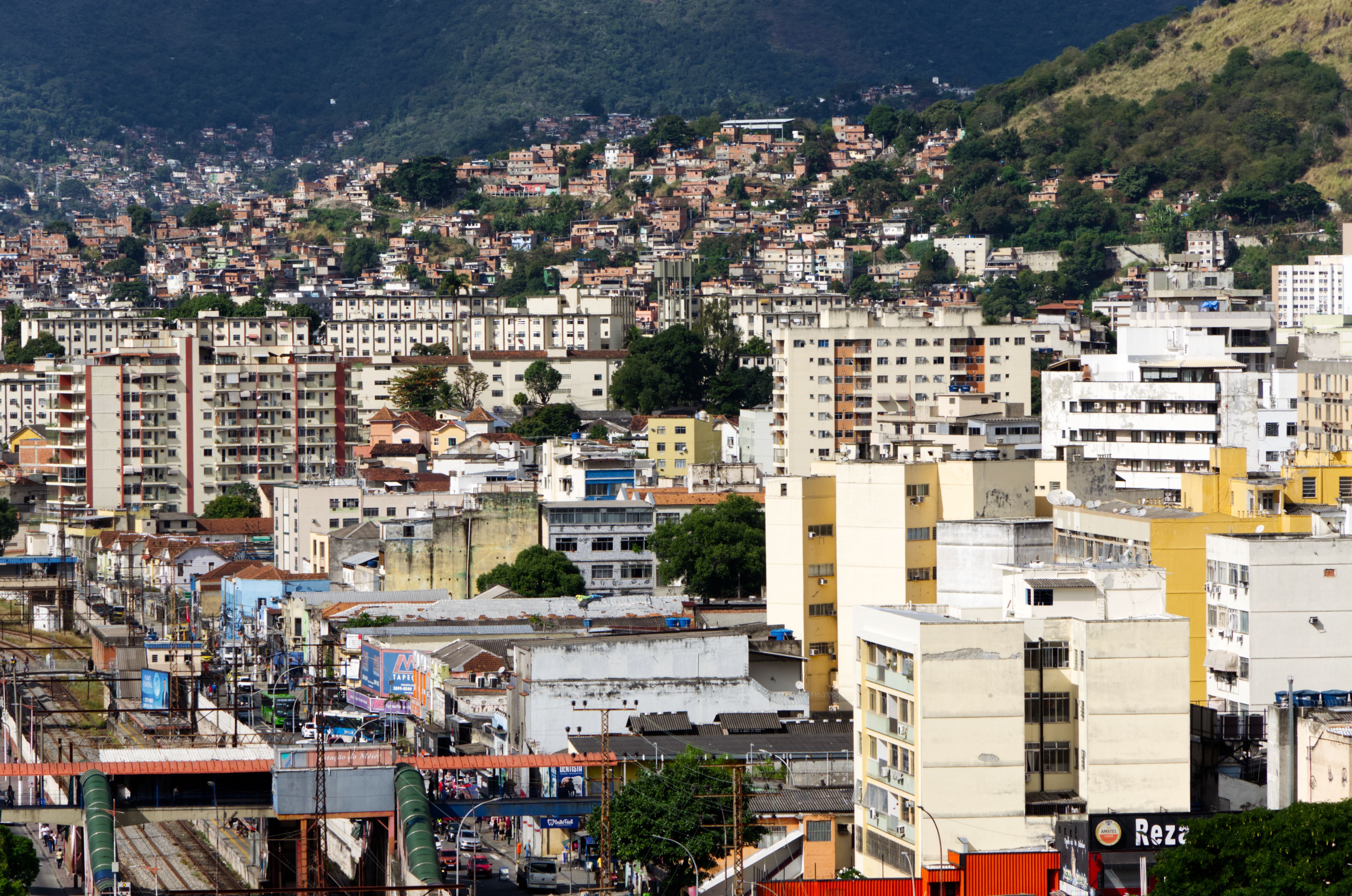 A bustling urban area with dense buildings and hills under a clear sky.