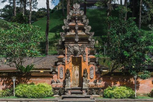 Free Entrance of ancient buddhist temple on hill surrounded by green trees on sunny day Stock Photo