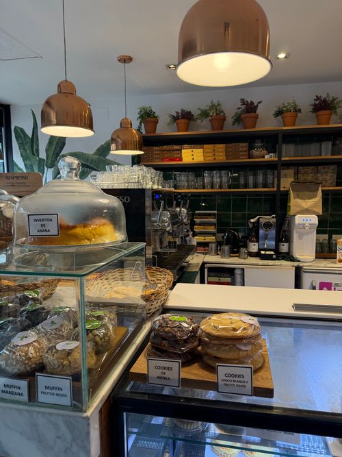 Free A warm cafe setting displaying pastries under glass domes and elegant decor, ideal for a relaxing visit. Stock Photo
