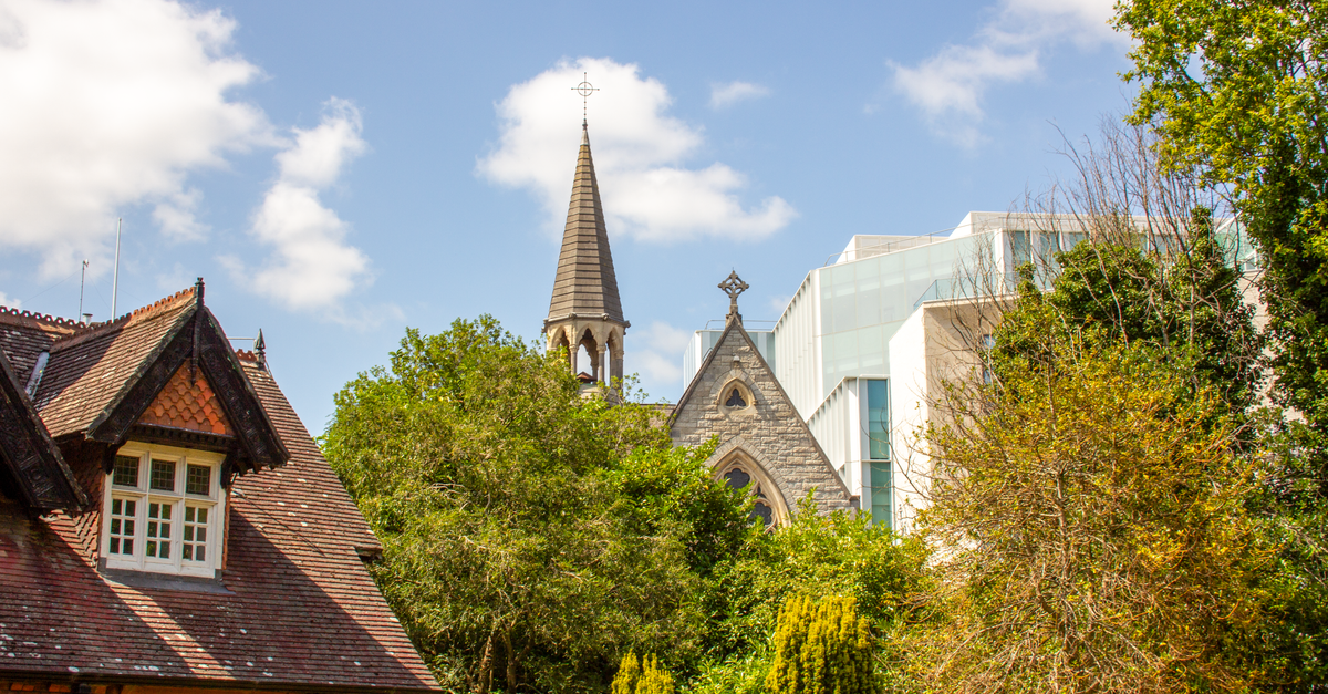 A picturesque mix of historic church and modern architecture amidst lush greenery in Dublin, Ireland.