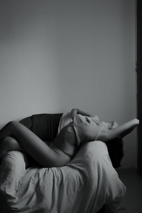 Free A dramatic black and white portrait of a woman reclining on a chair in a minimalist setting. Stock Photo