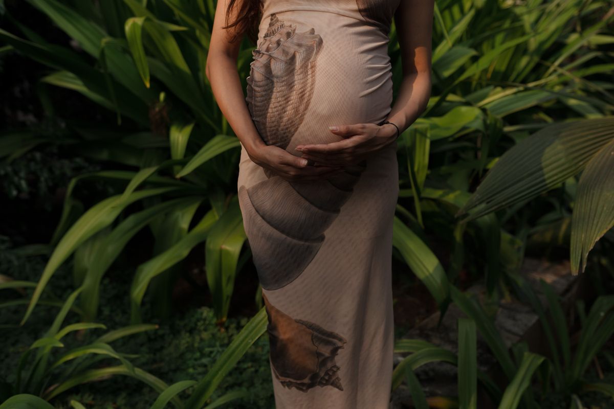 Futura madre disfrutando de un paseo en un jardín verde y luminoso