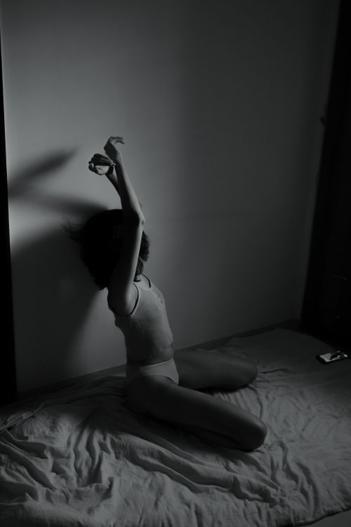 Free A woman sits gracefully on the floor in a minimalist setting, captured in black and white. Stock Photo