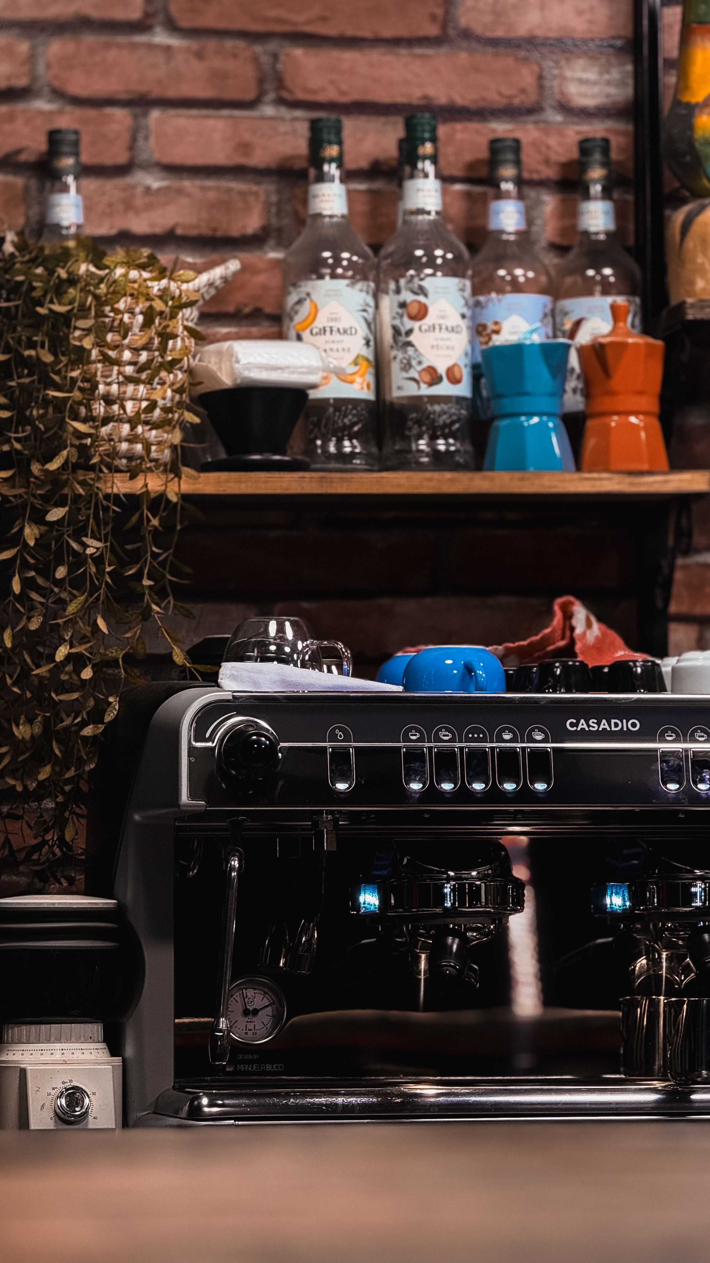 A sleek espresso machine in a rustic café, complemented by coffee accessories on a brick wall background.