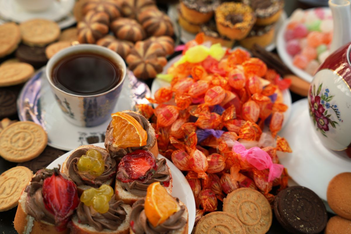 A vibrant spread of tea, colorful candies, and assorted baked goods displayed beautifully.