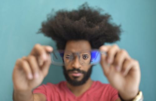 Free An adult man holds eyeglasses towards the camera with an intentional blur effect for depth. Stock Photo