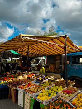 Colorful Italian market stall in Patti, Sicily, showcasing fresh fruits and vegetables under a striped canopy.