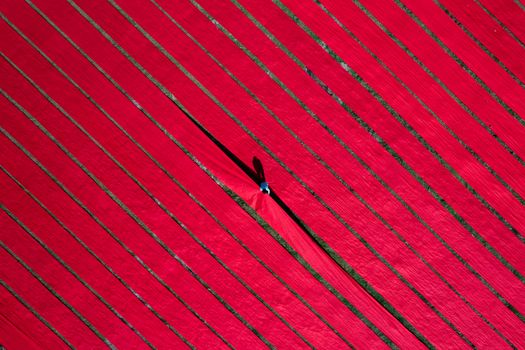 Aerial shot of red fabrics laid out to dry in Bangladesh, creating striking patterns.