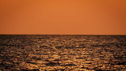 Free Peaceful ocean view at sunset with vibrant orange hues and shimmering reflections. Stock Photo