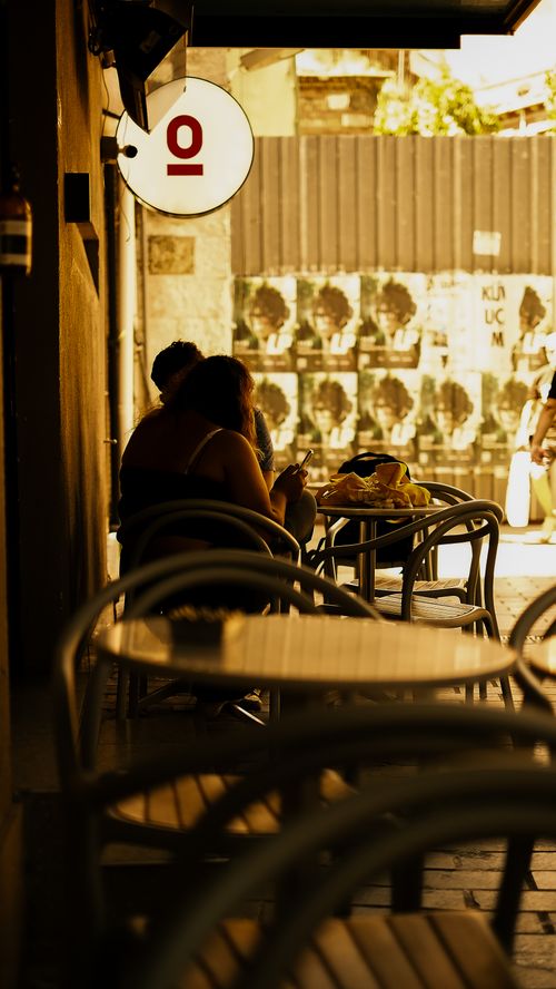 Free Shadowy café tables in an Istanbul street, evoking a warm urban atmosphere. Stock Photo