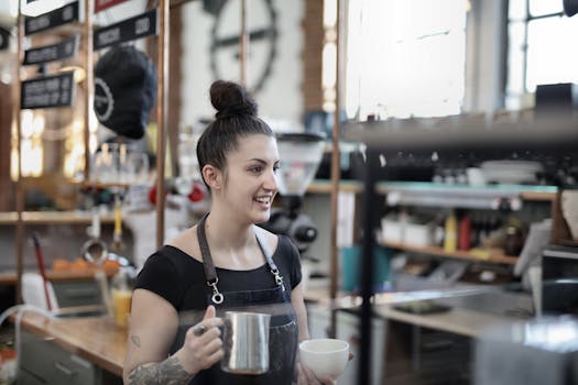 Barista smiling while preparing coffee at a bustling cafe counter.