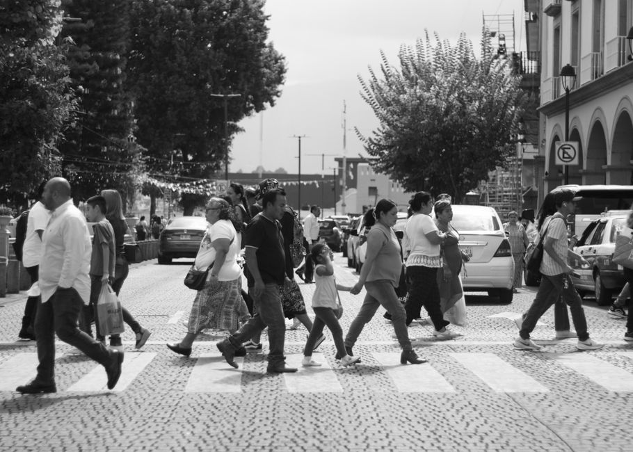 Peatones cruzando una calle en Xalapa, México, mostrando la vida urbana y la arquitectura.