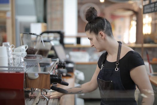 A barista expertly makes coffee at a modern café, using an espresso machine.