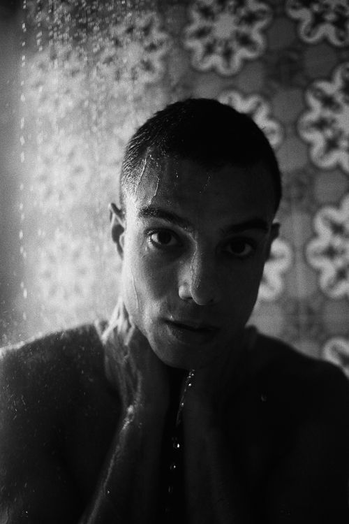 Free Dramatic black and white portrait capturing a man's intense expression while in the shower. Stock Photo
