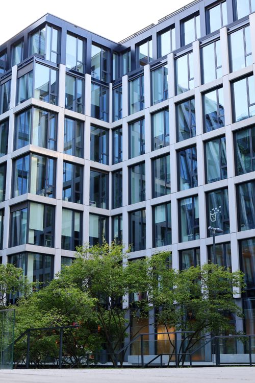 Free Contemporary glass building facade with trees, showcasing urban architecture style. Stock Photo