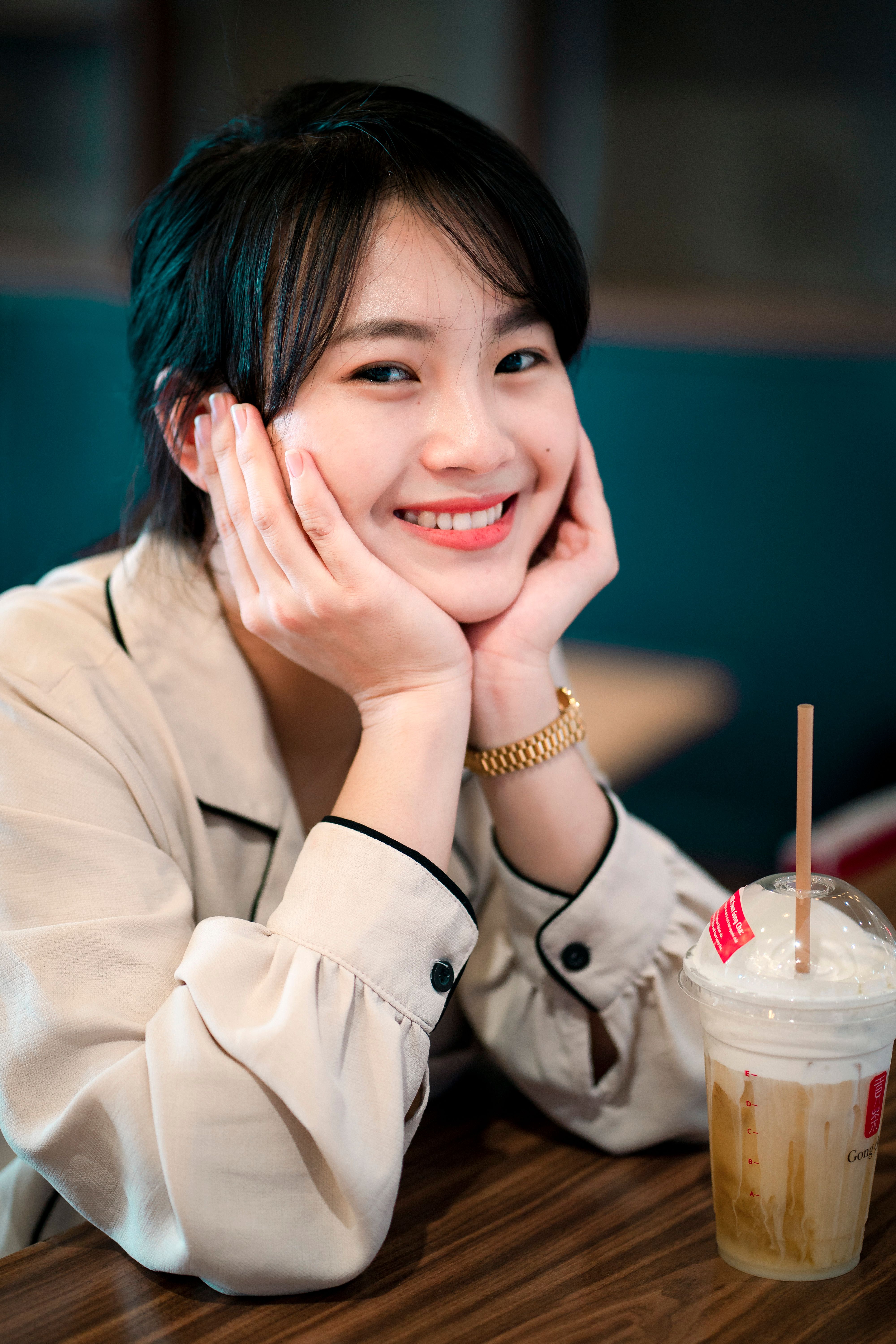 一位亚洲女子在室内微笑着喝咖啡，散发着温暖和幸福