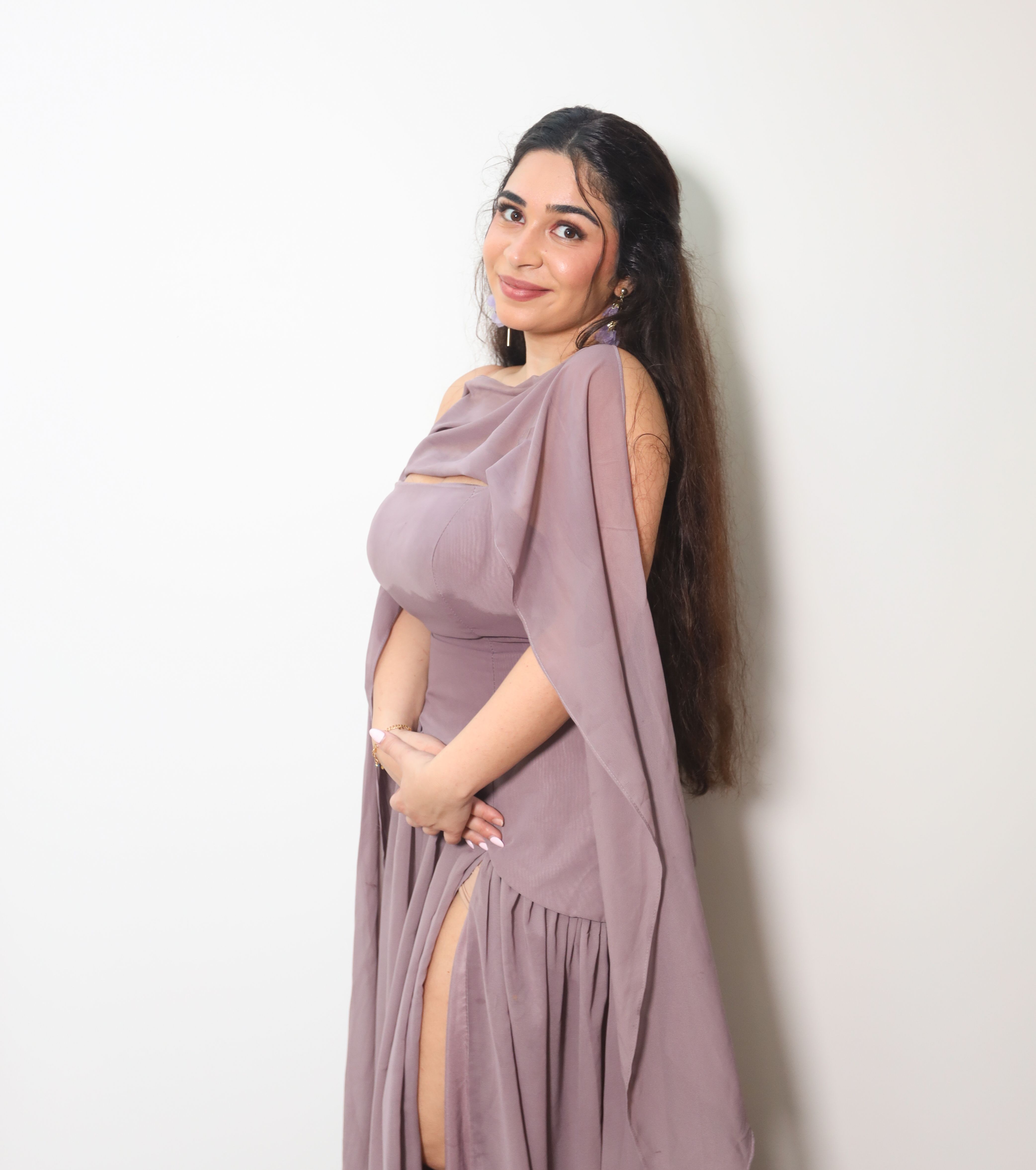 Portrait of a woman in a flowing lavender gown against a plain background.