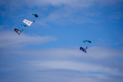 Free A thrilling aerial display with parachutists and flags under a vibrant blue sky. Stock Photo