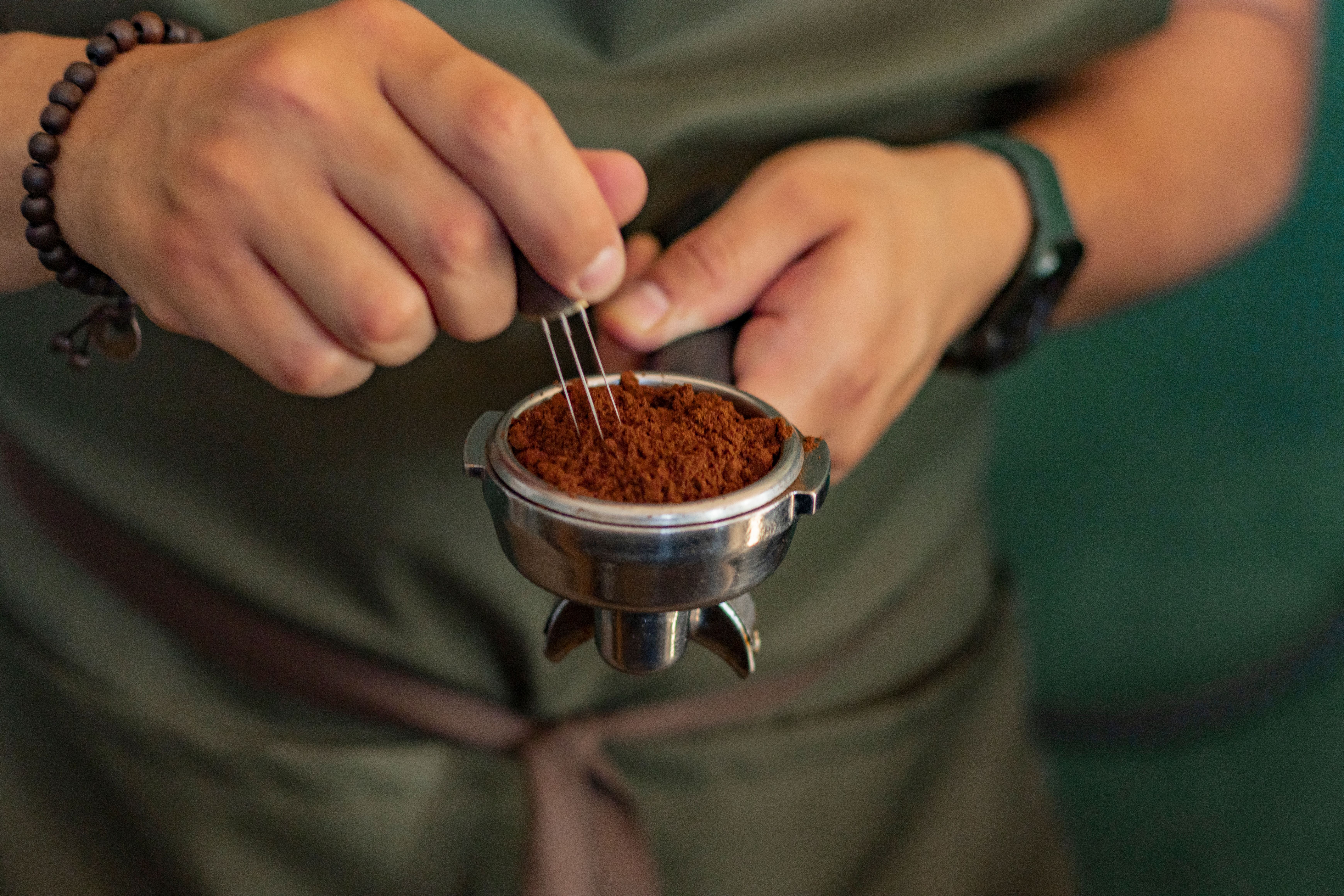 Close-up of a barista using a precision tool to prepare fresh espresso grounds.