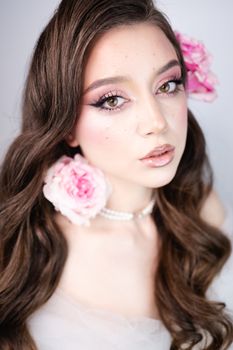 Close-up portrait of a woman with pink flowers and elegant makeup.