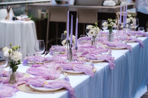 Free A beautifully arranged lavender table setting with flowers and candles for an outdoor event. Stock Photo