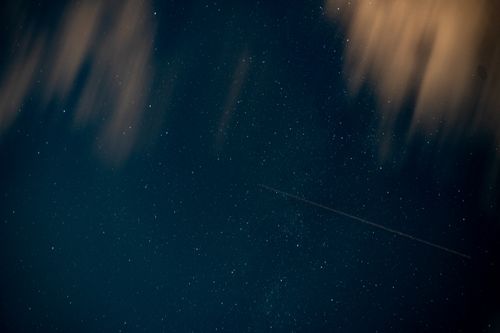 Free A stunning night sky featuring star clusters, a meteor streak, and blurred clouds creating a celestial spectacle. Stock Photo